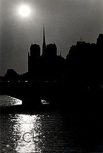 Black and white photo of the gothic cathedral Notre Dame rising above the Seine in Paris, France