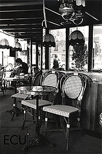 Black and White photo of the historic Café La Rotonde and brasserie with chairs facing the Boulevard Montparnasse in Paris, France