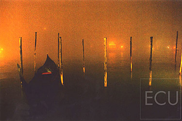 Color photograph of gondolas at night on the Grand Canal in fog in winter in Venice, Italy