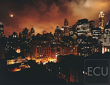 Color photograph of the lights of midtown Manhattan at night with clouds taken from Madison Avenue and East 63rd Street in New York, NY